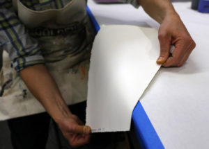 Demonstrating how to oppose paper warp by running paper over the edge of a table.