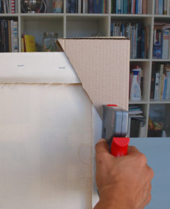 The corner protection is stapled to the reverse of a canvas painting.